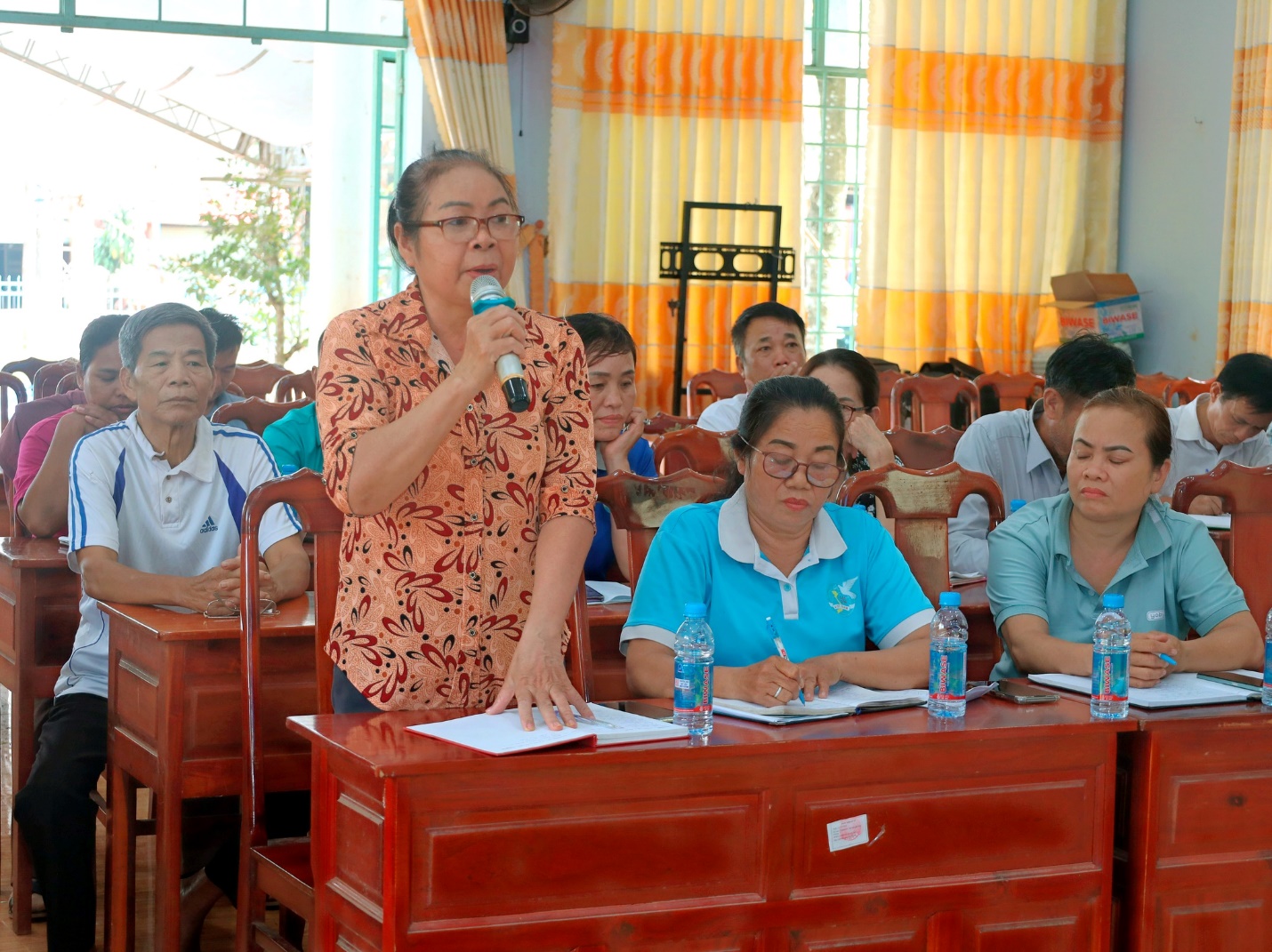 'A person speaking into a microphone in a classroom

Description automatically generated'