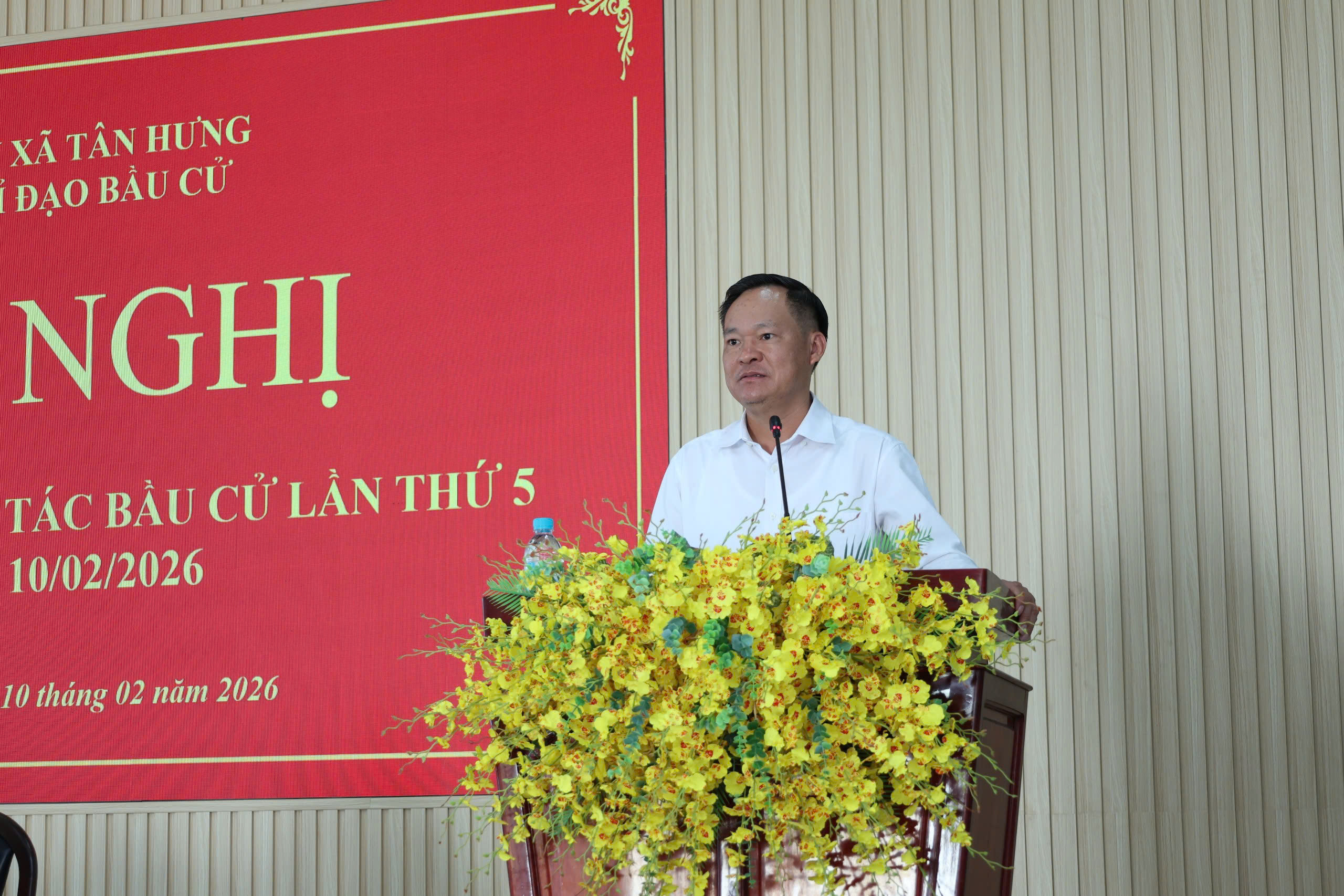 'A person standing at a podium with flowers

Description automatically generated'