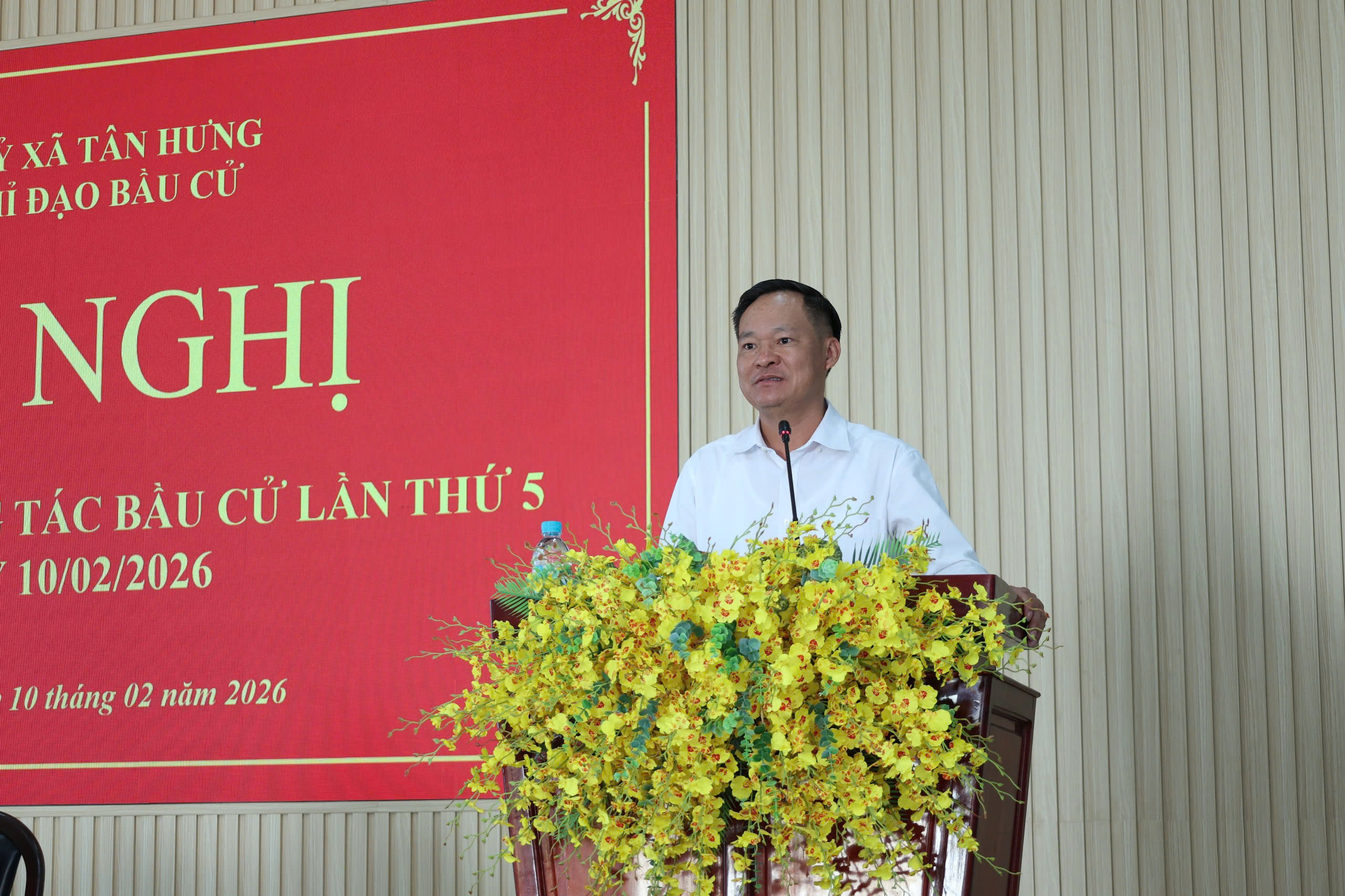 'A person standing at a podium with yellow flowers

Description automatically generated'