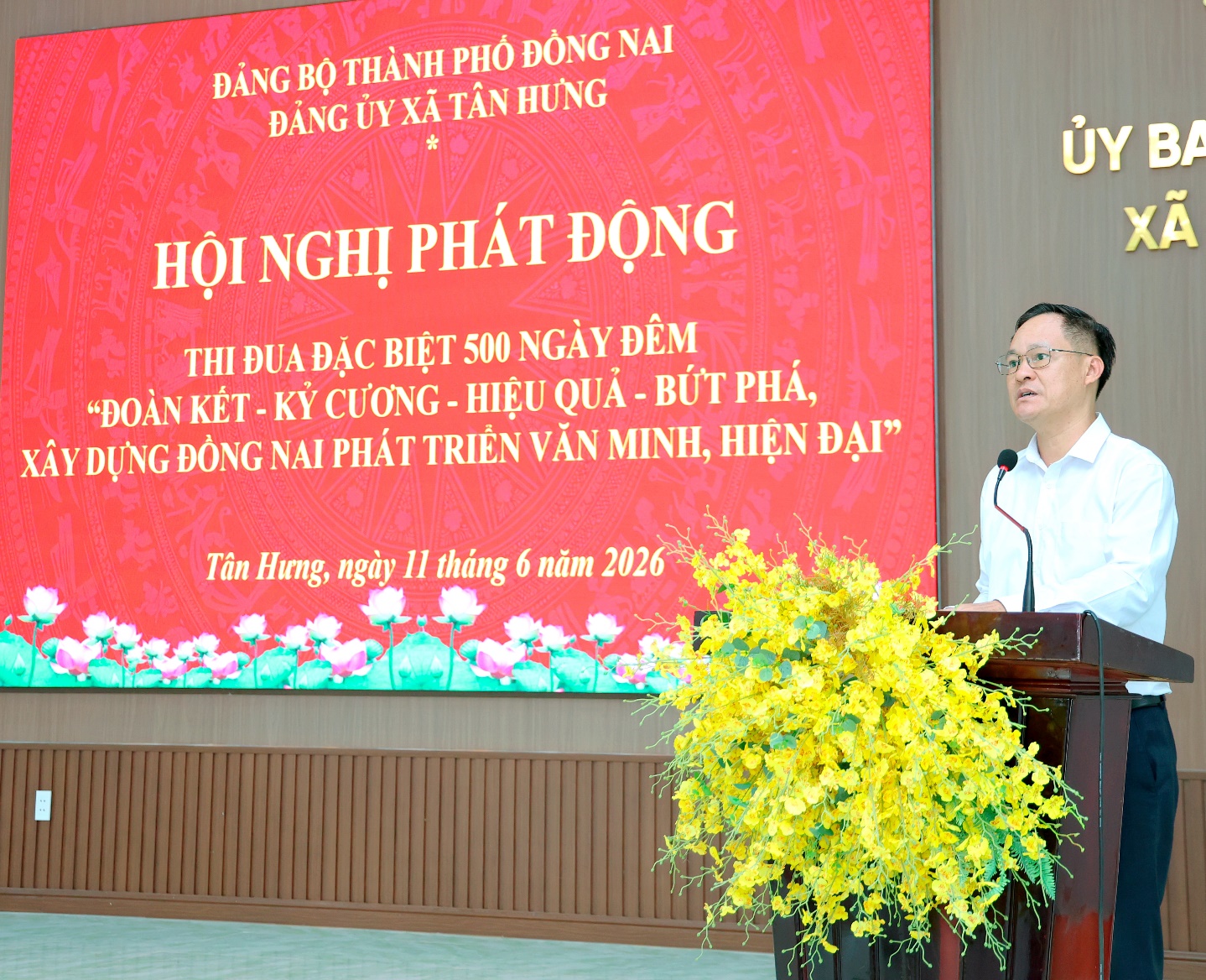 'A person standing at a podium with a large screen behind him

Description automatically generated'