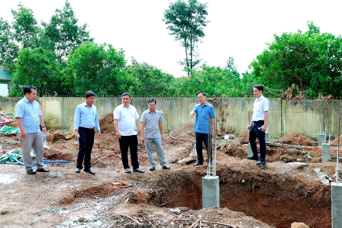 A group of men standing in a dirt area

Description automatically generated
