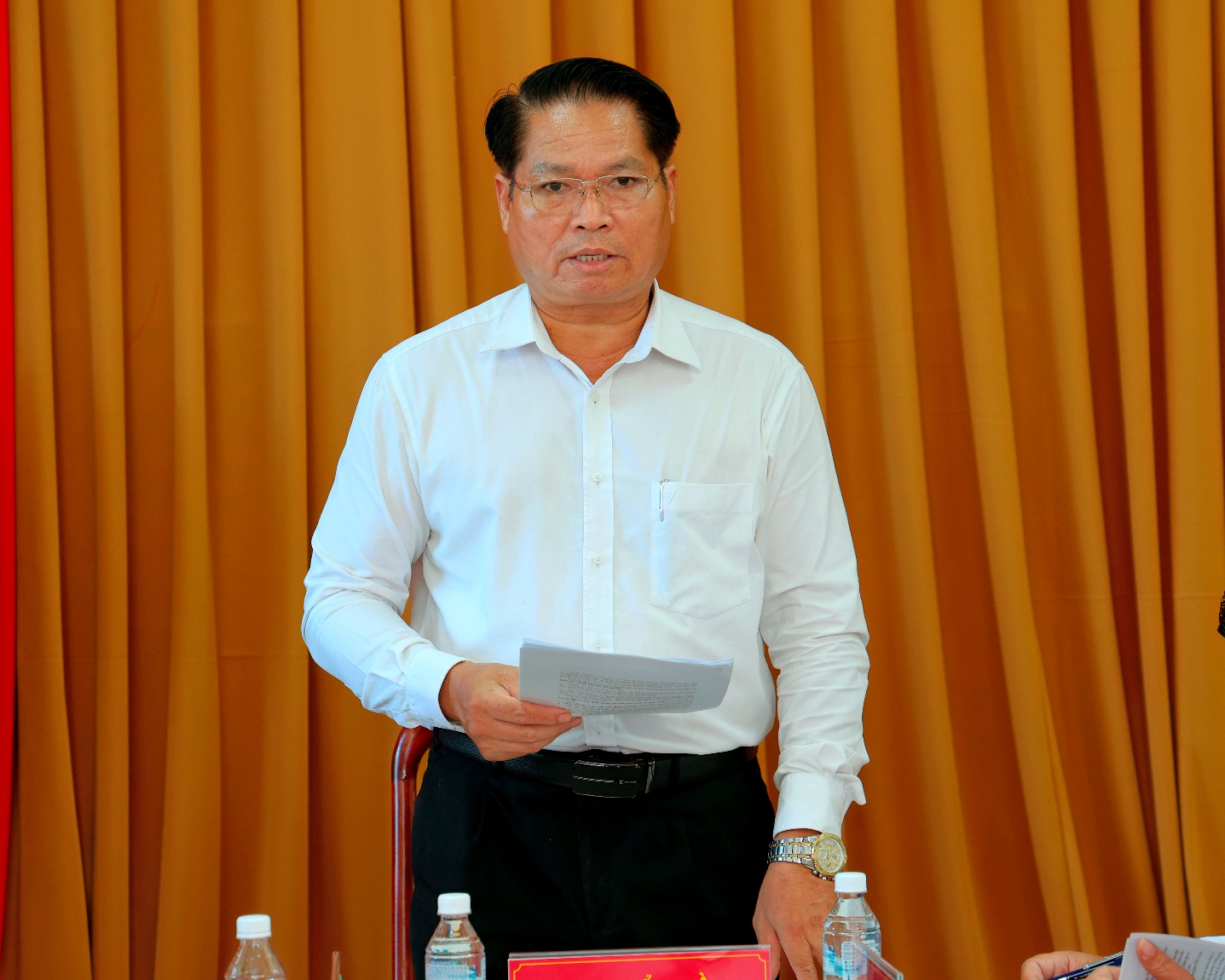 A person standing in front of a table with a paper

Description automatically generated