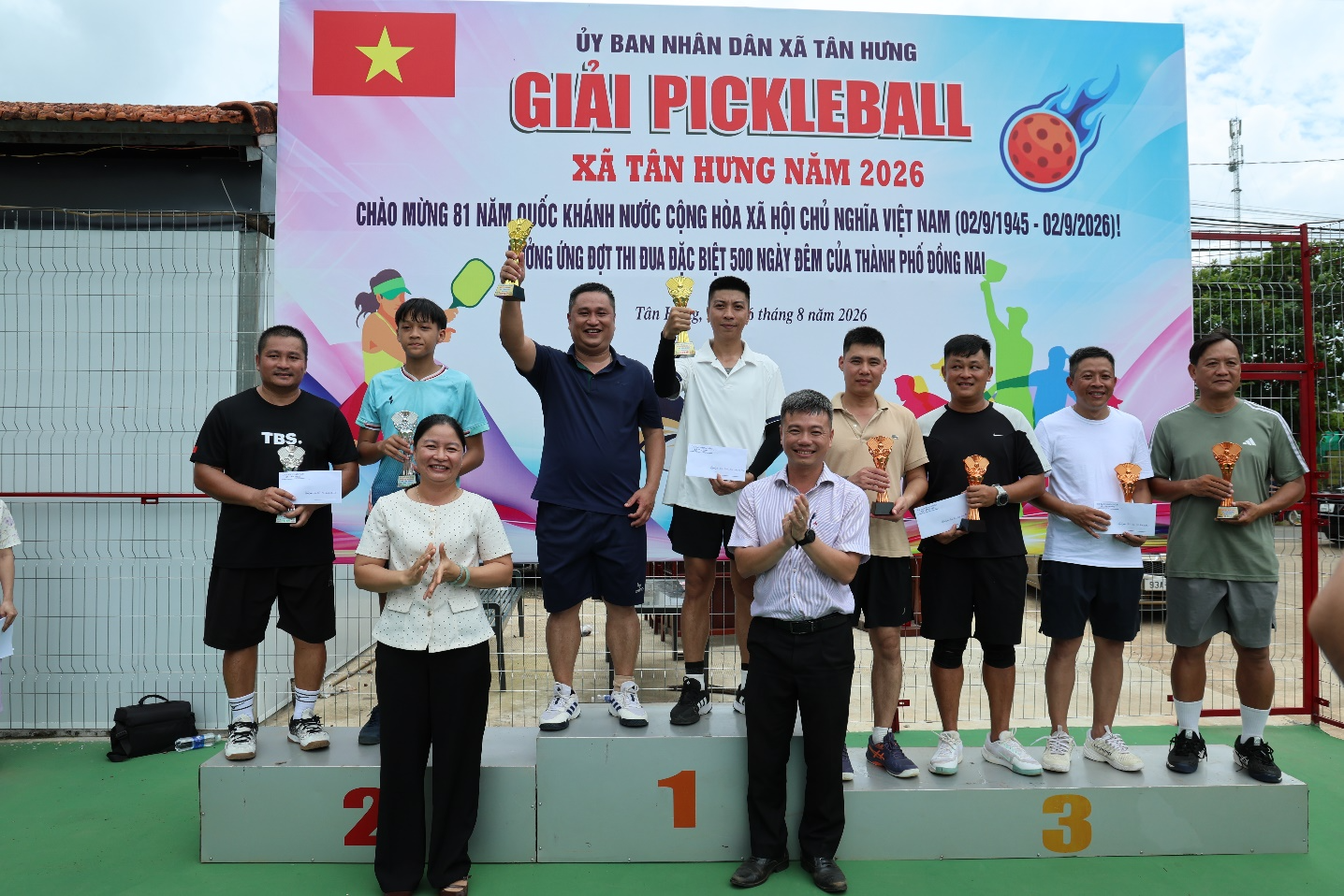 A group of people standing on a podium holding trophies

Description automatically generated