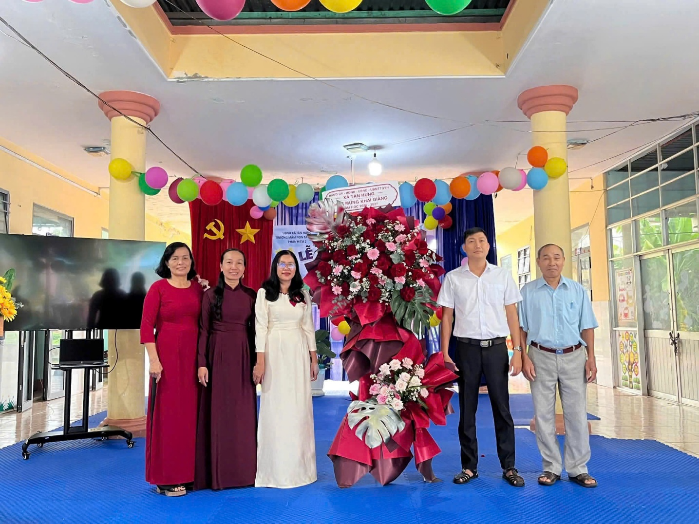 A group of people standing in front of a large flower arrangement

Description automatically generated