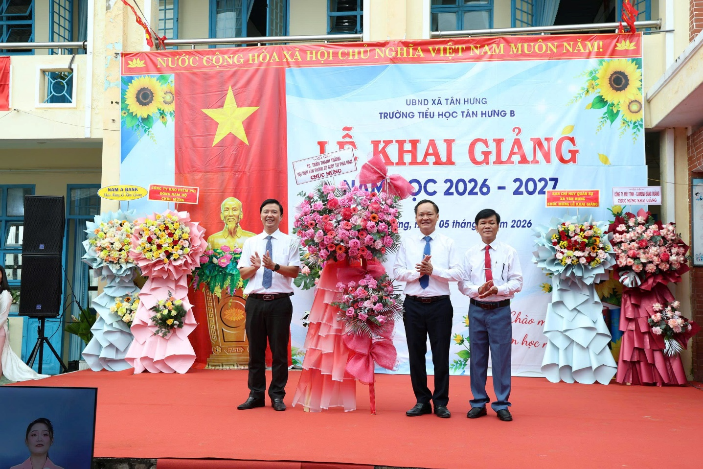 A group of men standing on a stage with flowers

Description automatically generated